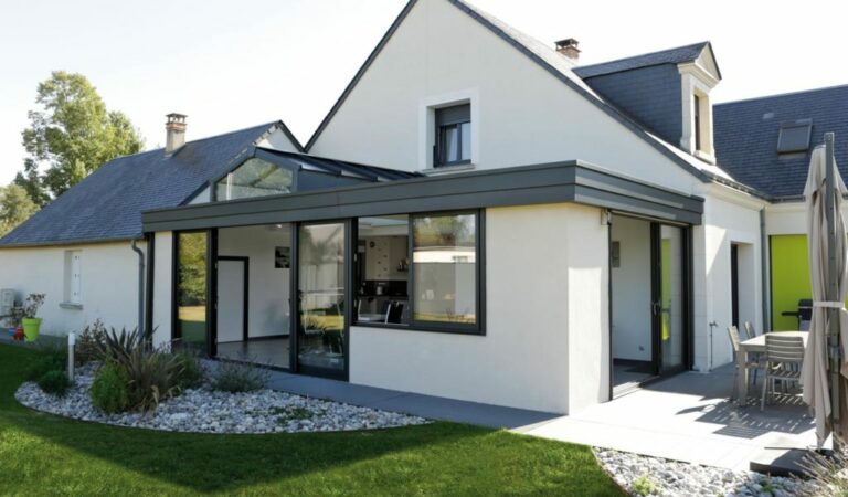 Véranda moderne blanche agrandissant une maison avec grandes baies vitrées