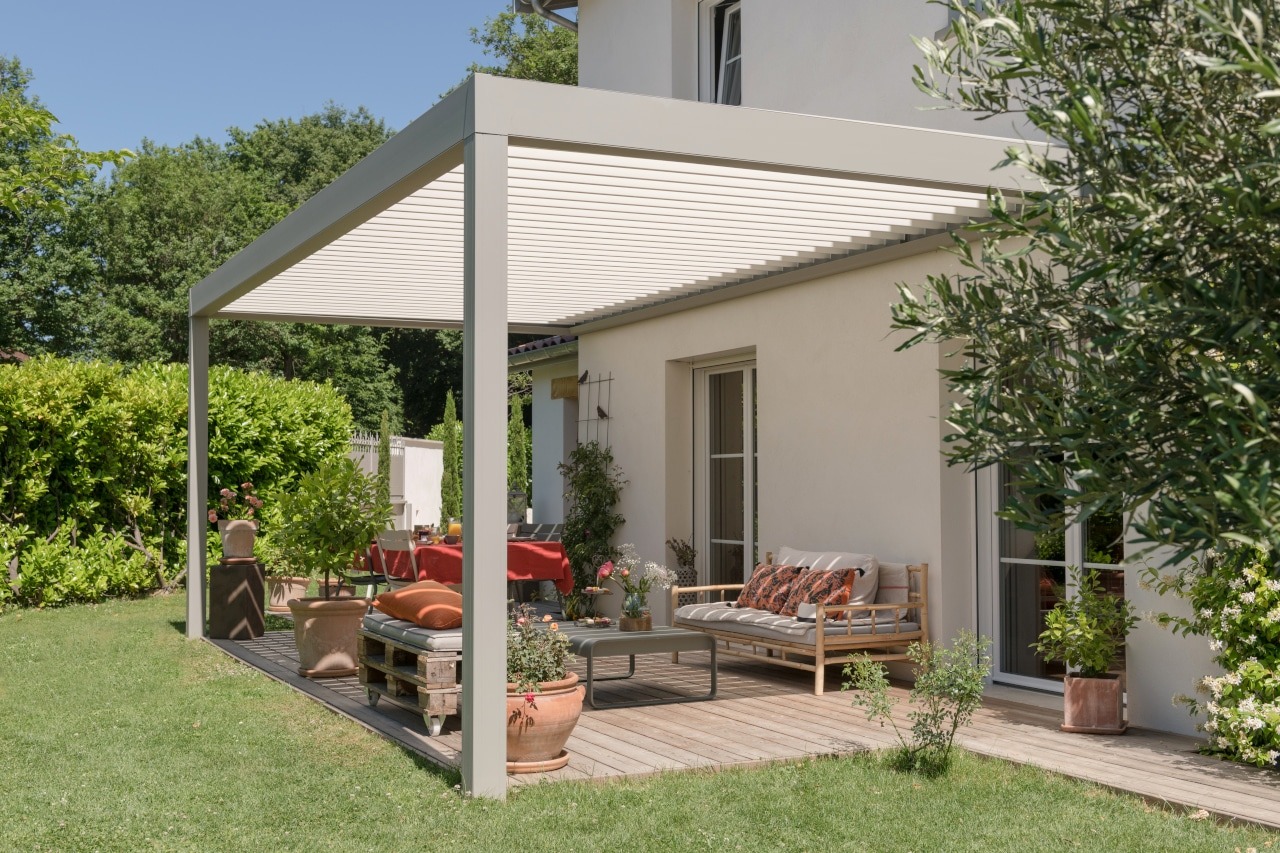 Pergola blanche à lames orientables sur terrasse en bois